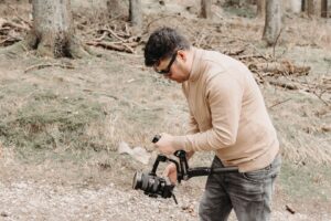 Filmskapare justerar en videokamera under inspelning i skogen