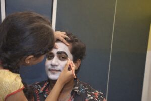 Sminkör målar vita basen och markerar ögonbryn på skådespelare