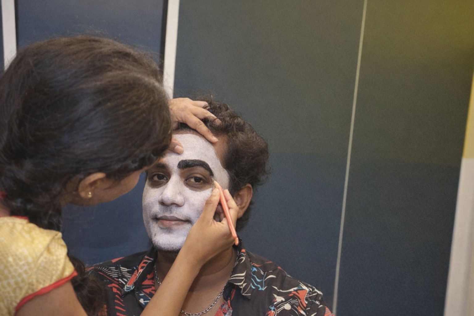 Sminkör målar vita basen och markerar ögonbryn på skådespelare