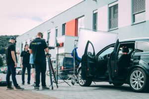Ett filmteam filmar en bil med professionell utrustning utomhus.